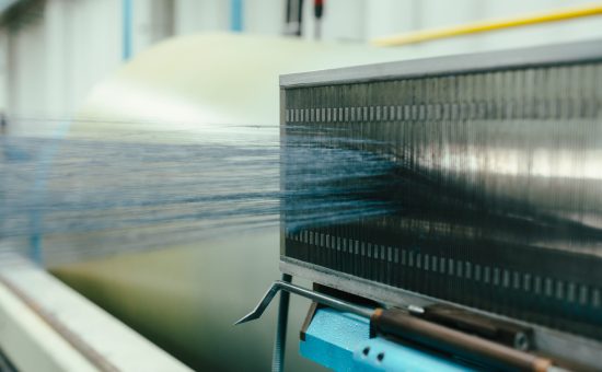 Blue yarn strands being woven through a loom in industrial textile production
