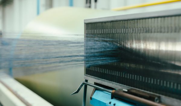 Blue yarn strands being woven through a loom in industrial textile production