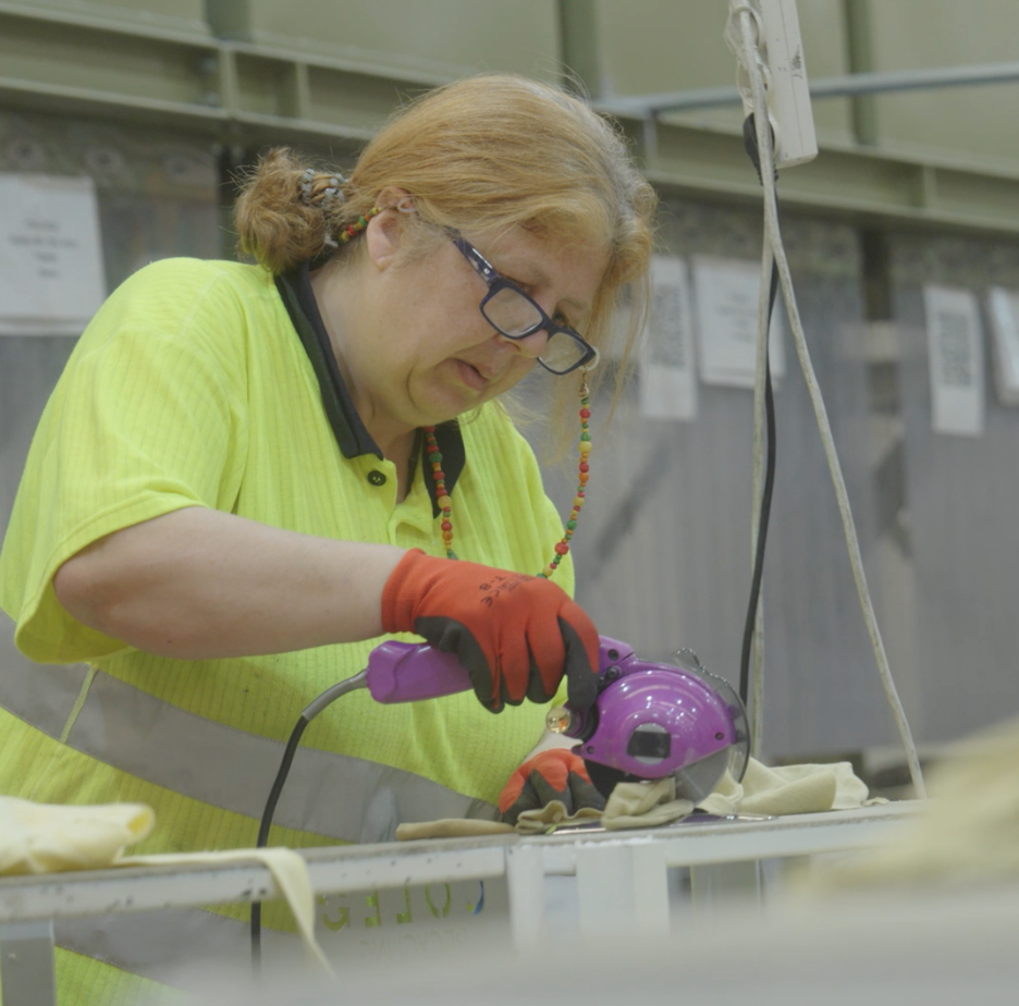 Woman with electric scissors cutting fabric at Coleo facility